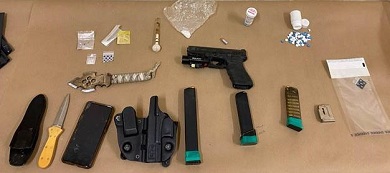 Picture of gun, magazines, holster, knives, and drugs